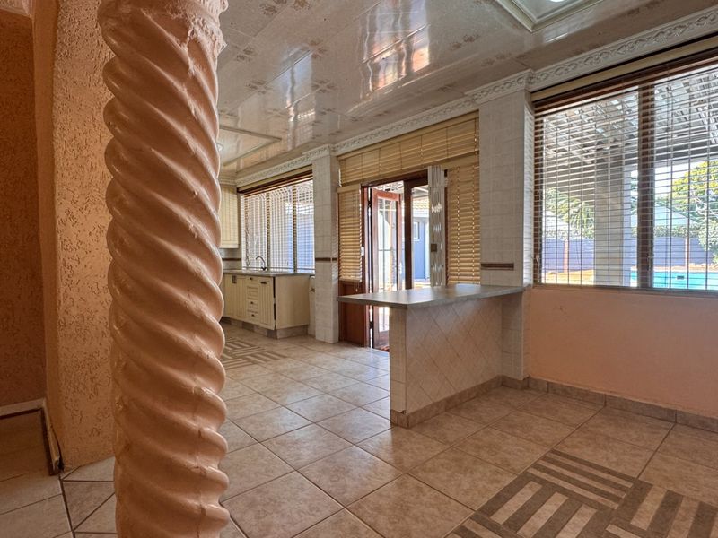 Open plan living and kitchen area featuring a decorative spiral column, tiled flooring, breakfast bar, and direct access to the outdoor pool area.