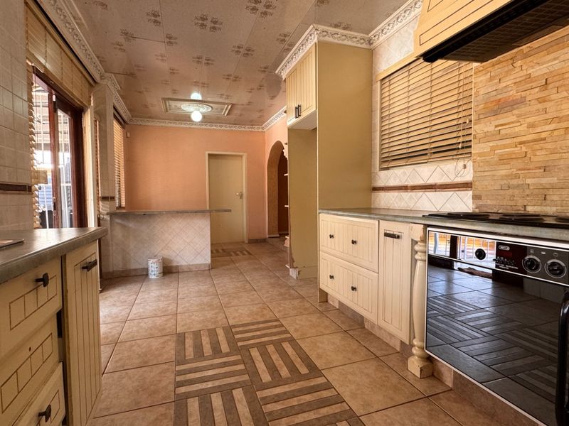 Spacious kitchen featuring built-in cabinetry, stone tile backsplash, integrated oven, and a breakfast bar, offering a functional layout ready for modern updates.