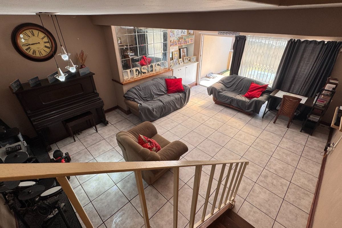 Spacious living area featuring tiled flooring, a staircase with a railing, and direct access to an outdoor patio through a sliding glass door.