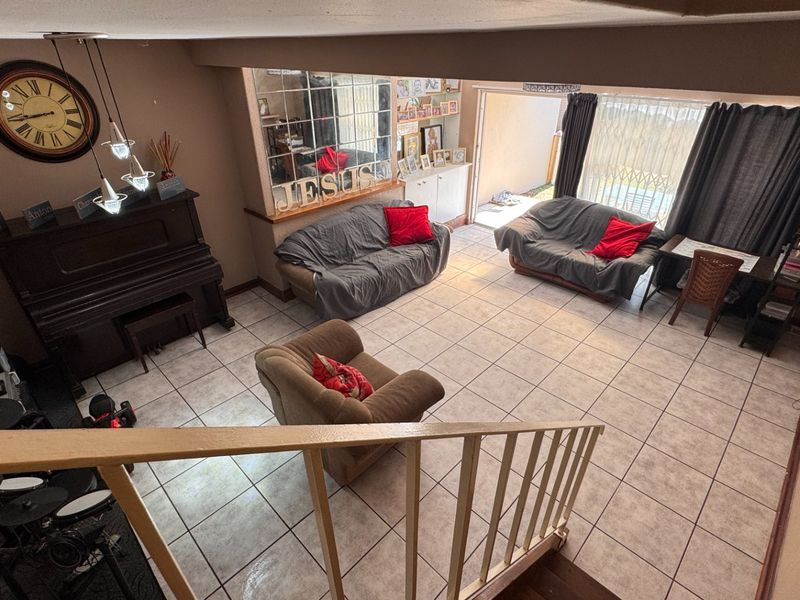 Spacious living area featuring tiled flooring, a staircase with a railing, and direct access to an outdoor patio through a sliding glass door.