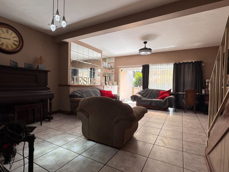 Spacious living area featuring tiled flooring, a mirrored wall accent, and direct access to the outdoor patio through sliding glass doors.