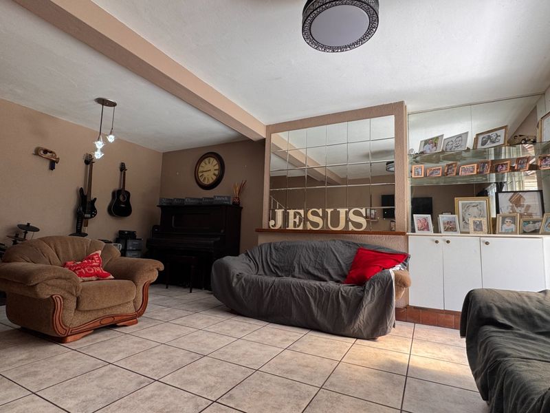 Spacious living room featuring tiled flooring, a decorative mirrored wall, and built-in storage cabinetry, offering a functional layout for relaxation.