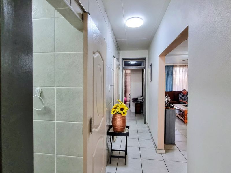 A functional hallway featuring tiled flooring and walls, providing access to adjacent living areas and rooms within the apartment.