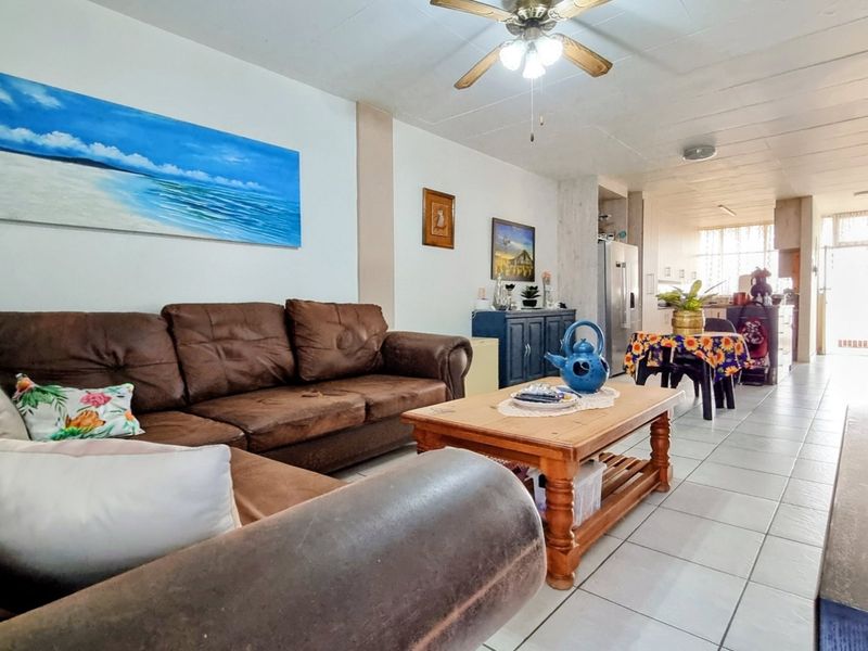 Open-plan living and dining area featuring tiled flooring, a ceiling fan, and a connected kitchen space with built-in cabinetry.