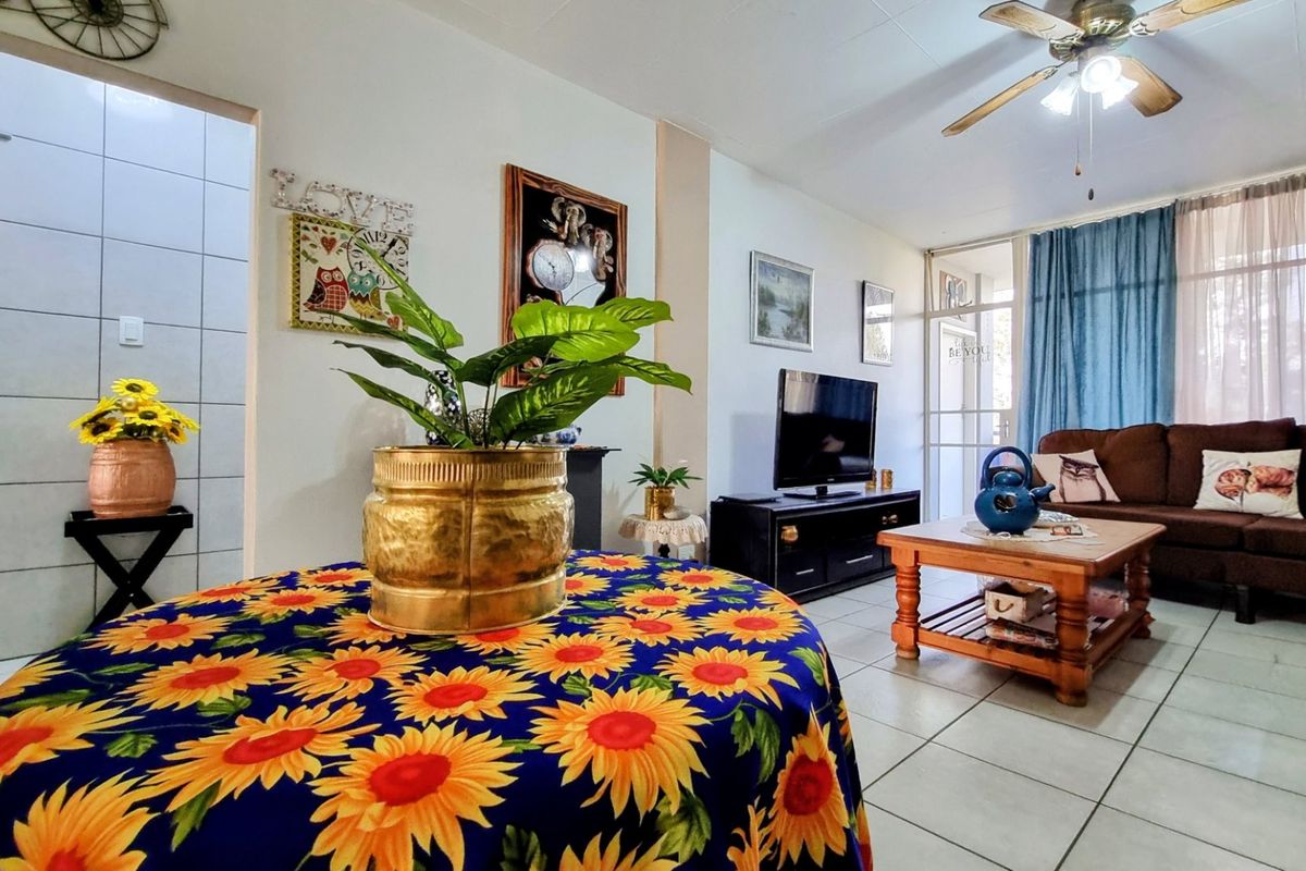 A living room area featuring tiled flooring, a ceiling fan, and access to an outdoor space through a sliding glass door.