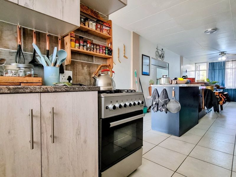 Open-plan kitchen and living area featuring tiled flooring, a central kitchen island, and a freestanding stove with oven.