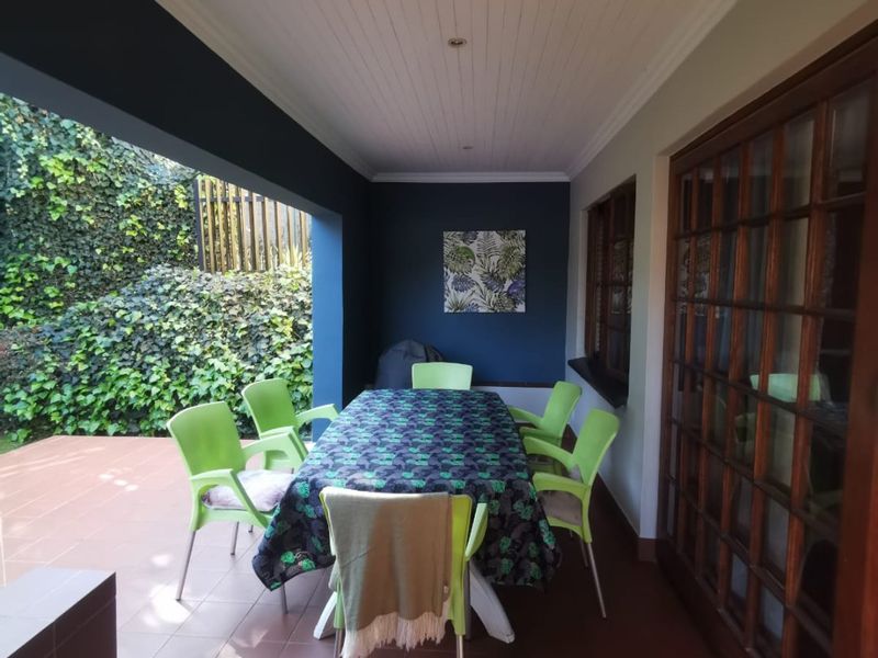 A covered outdoor patio featuring tiled flooring, timber-framed glass doors, and a tongue and groove ceiling, providing a functional space for outdoor dining.