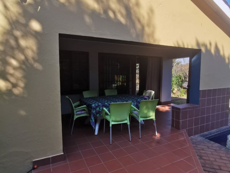 A covered outdoor patio area featuring tiled flooring and wall cladding, providing a functional space for outdoor dining and relaxation.