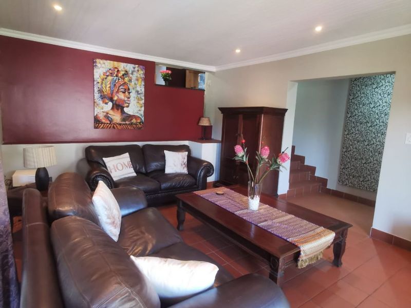 Spacious living room featuring terracotta floor tiles, a tongue and groove ceiling with recessed lighting, and a distinct red accent wall.