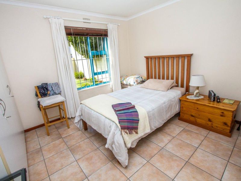 A functional bedroom featuring tiled flooring, a built-in wardrobe, and security bars on the window, providing a practical and secure living space.