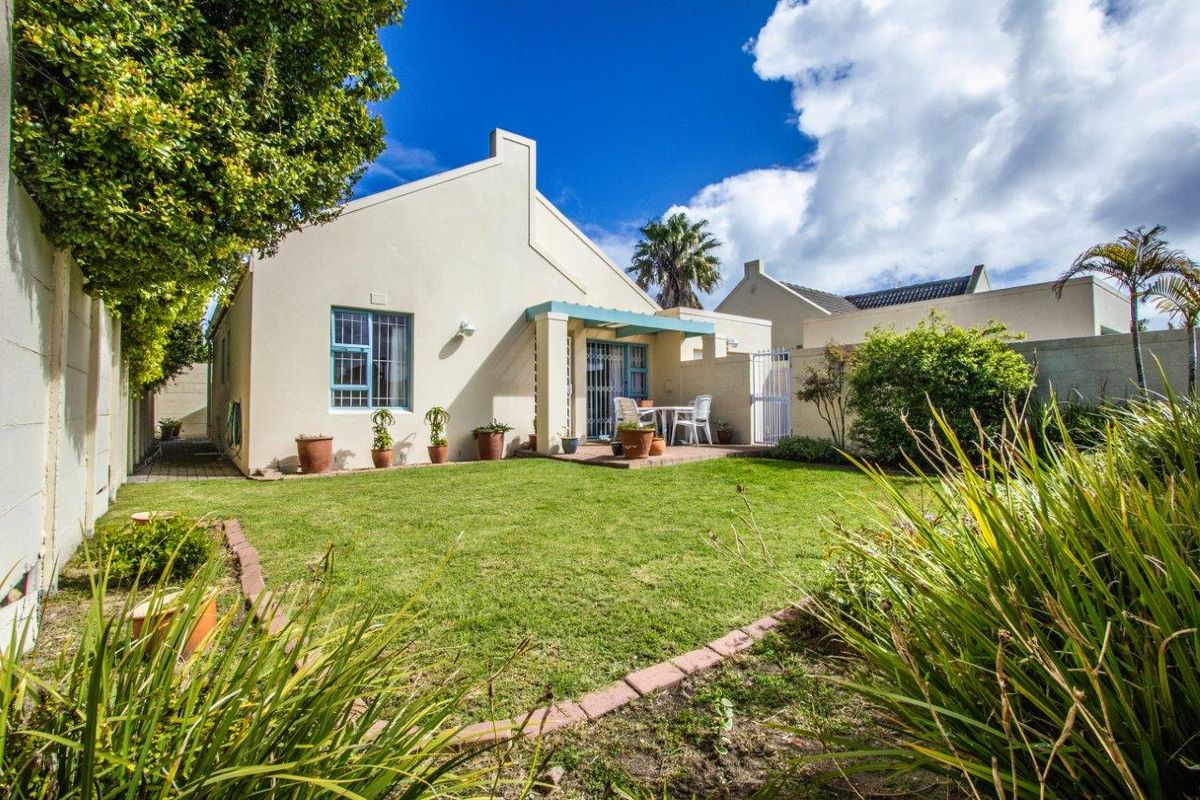 A well-maintained rear garden featuring a paved patio area, established lawn, and secure boundary walls, providing a private outdoor space.