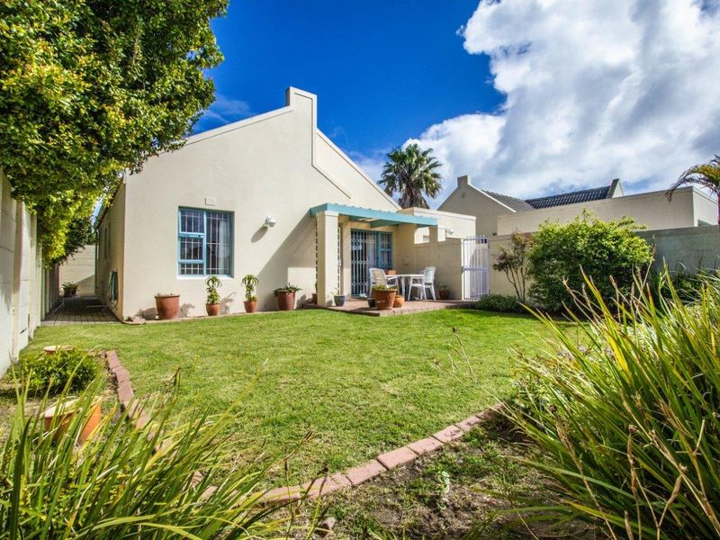 A well-maintained rear garden featuring a paved patio area, established lawn, and secure boundary walls, providing a private outdoor space.