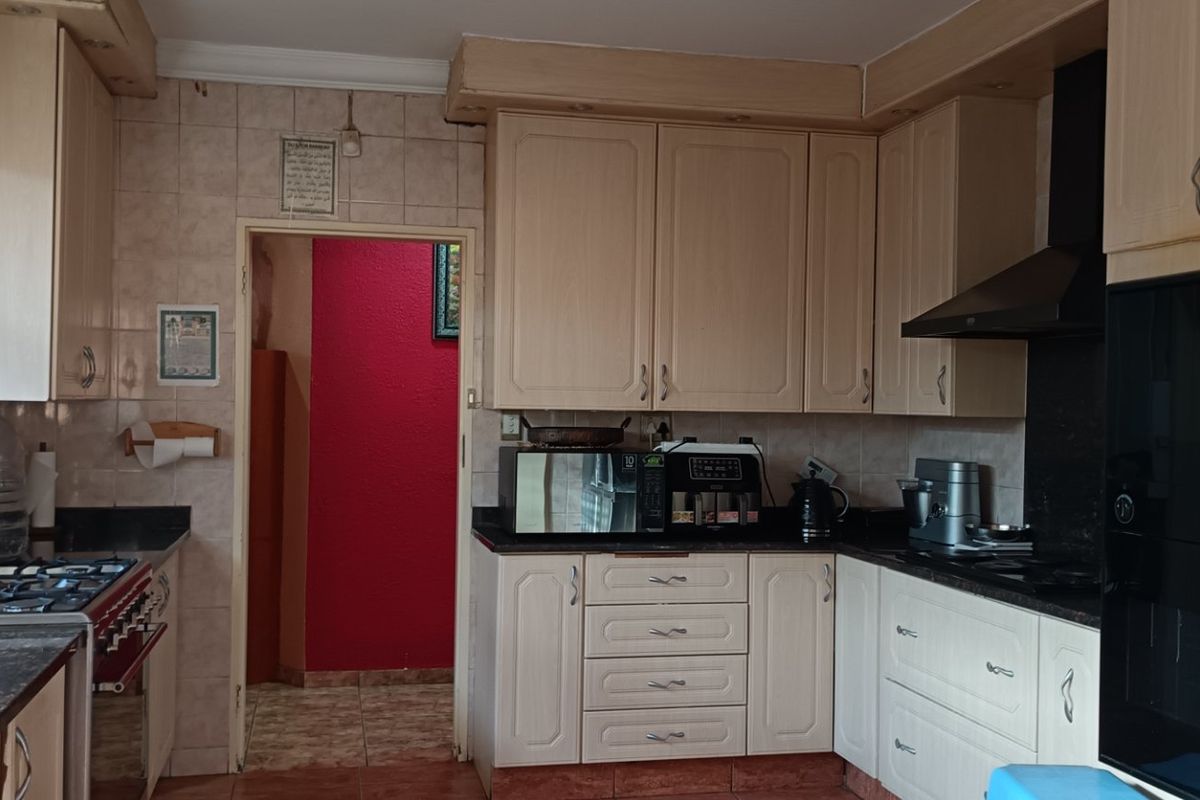 A functional kitchen featuring light-toned built-in cabinetry, granite countertops, a gas stove, and an integrated oven with a black extractor fan.