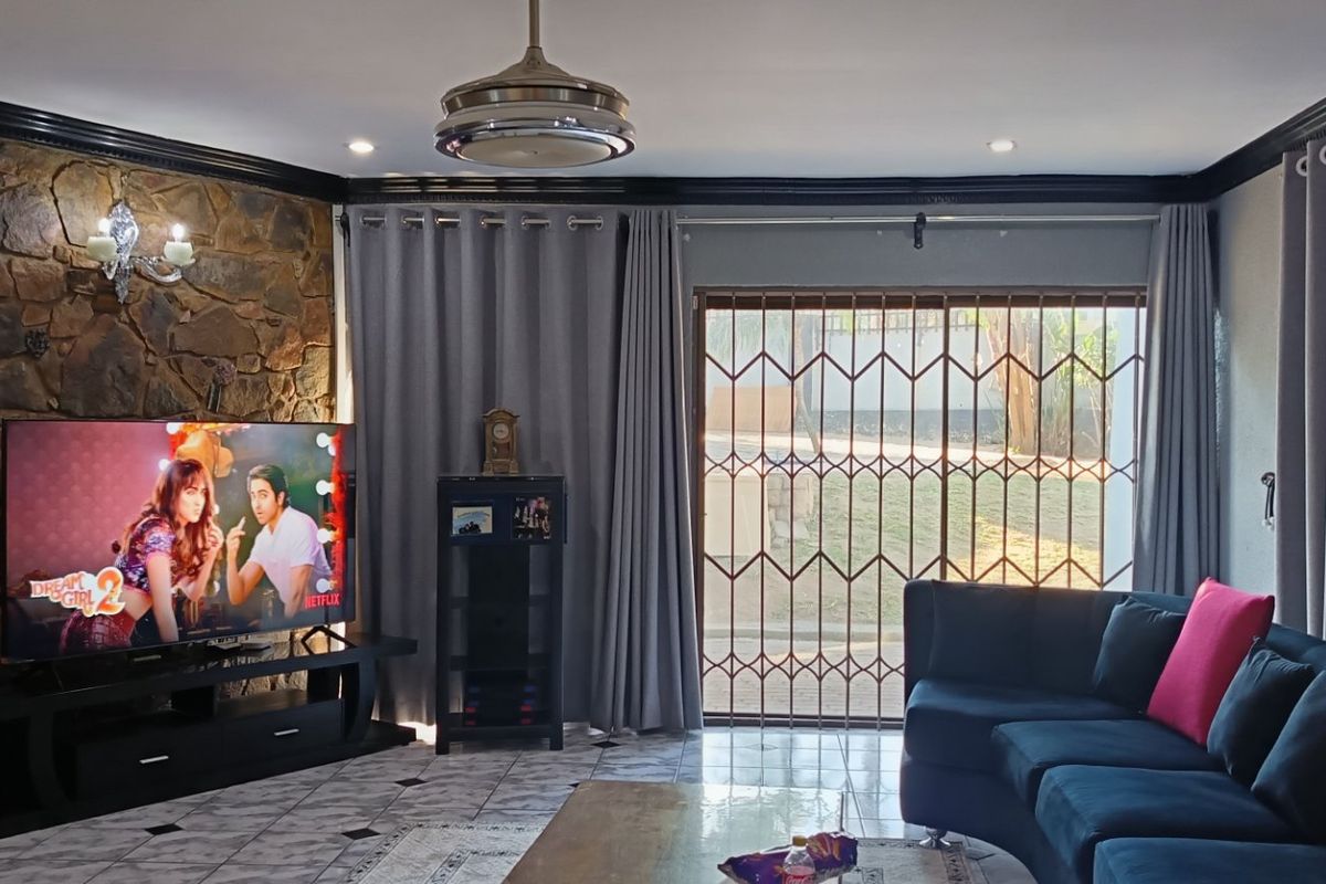 A comfortable living room featuring a prominent stone accent wall, tiled flooring, recessed lighting, and a secure sliding door leading to the exterior.