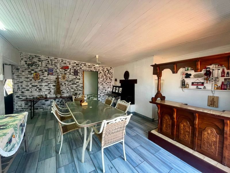 Spacious living area featuring a built-in wooden bar, fireplace, exposed brick wall, and modern tiled flooring, offering a versatile entertainment space.