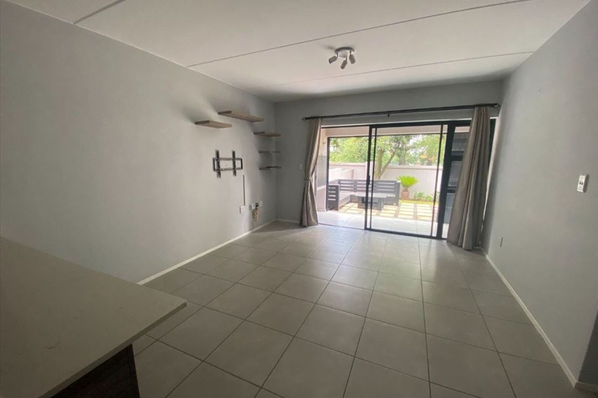 Spacious living area with neutral tiled flooring and large sliding glass doors providing direct access to the outdoor patio.