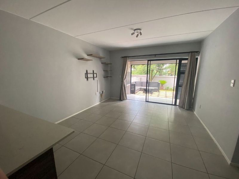 Spacious living area with neutral tiled flooring and large sliding glass doors providing direct access to the outdoor patio.