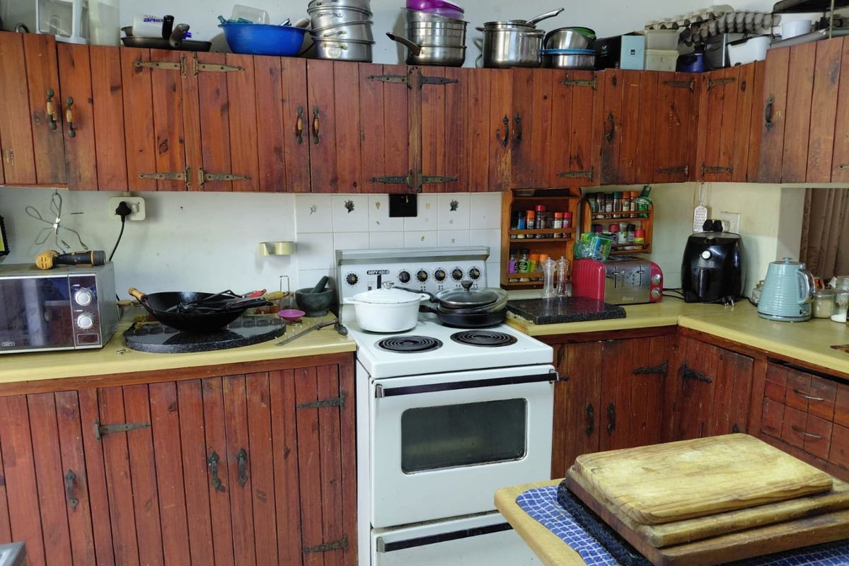 A functional kitchen featuring traditional wooden cabinetry, a freestanding stove, and tiled backsplash, offering potential for a modern cosmetic update.