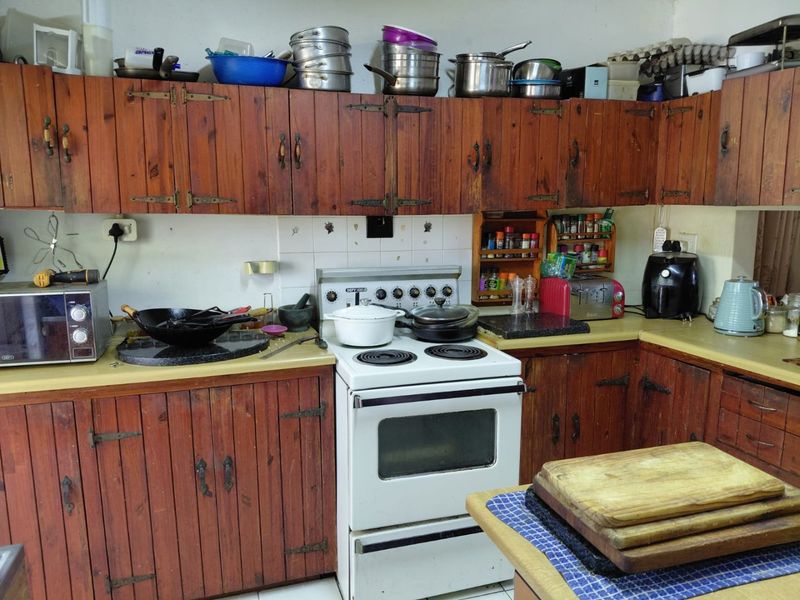 A functional kitchen featuring traditional wooden cabinetry, a freestanding stove, and tiled backsplash, offering potential for a modern cosmetic update.