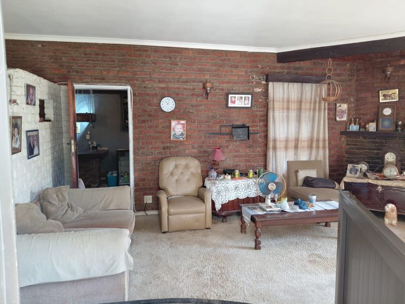 A living room featuring exposed brick walls, a fireplace, and an exposed timber beam, offering a rustic foundation for potential modernization.