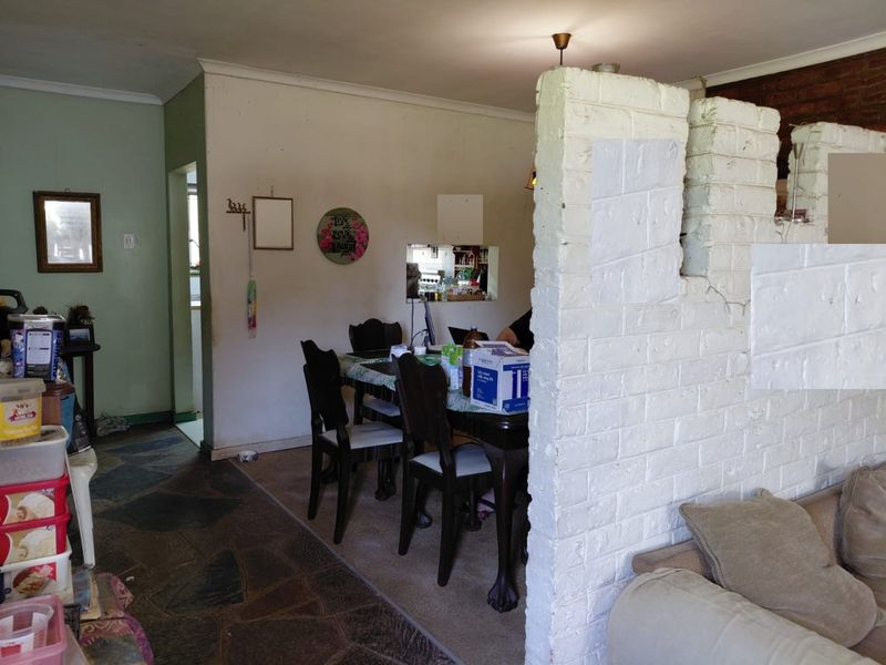 Open plan living and dining area featuring a painted brick partition wall, mixed stone and carpet flooring, and a functional layout.