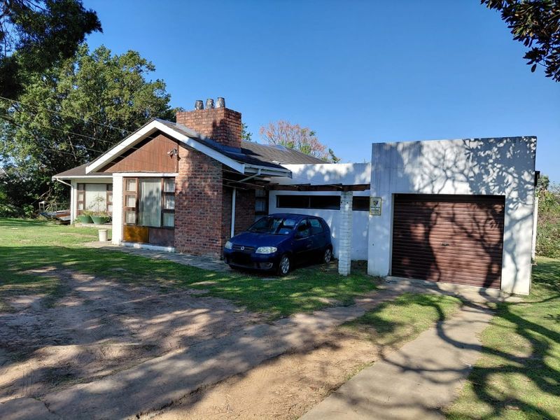 Front elevation of a single-story house featuring a brick chimney, timber cladding, and an attached garage with a roller door.