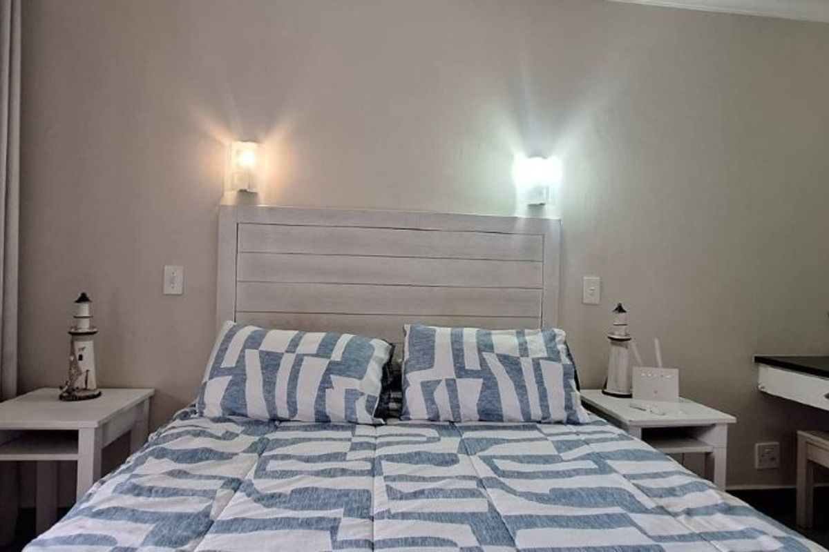 A well-maintained bedroom featuring wall-mounted lighting, a built-in vanity area, and neutral wall finishes.