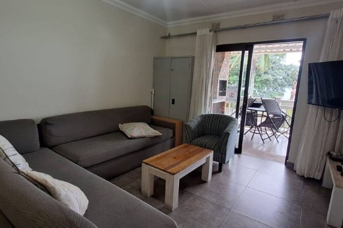 A comfortable living room featuring tiled flooring and a sliding glass door that provides direct access to an outdoor patio area.