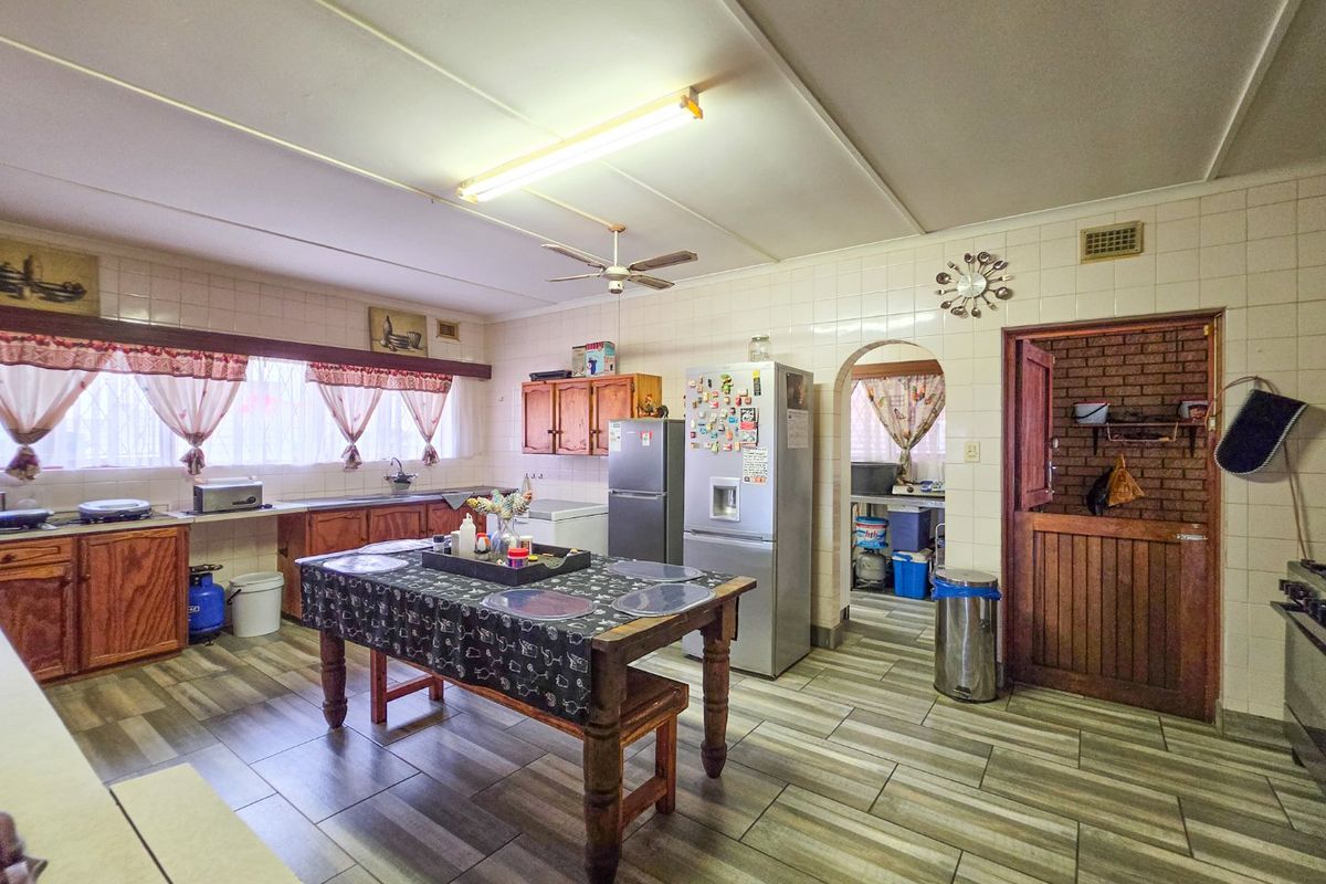 Spacious kitchen featuring wooden cabinetry, tiled splashbacks, and a stable door leading to a secondary area, offering a functional layout with potential for modernization.