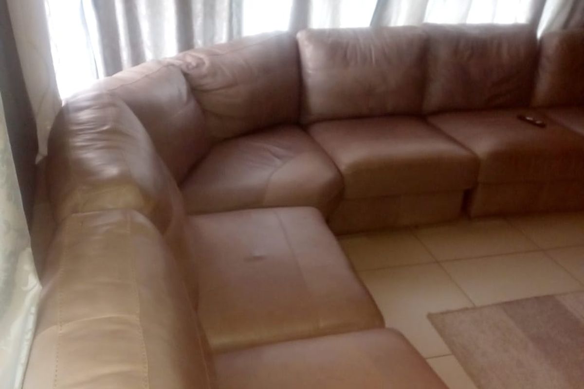 A living room area featuring tiled flooring and large windows with curtains.