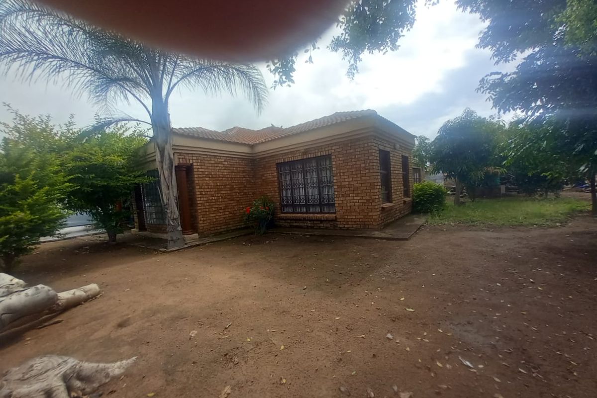 A view of the rear face brick exterior of the house, featuring a tiled roof and security bars on the windows.