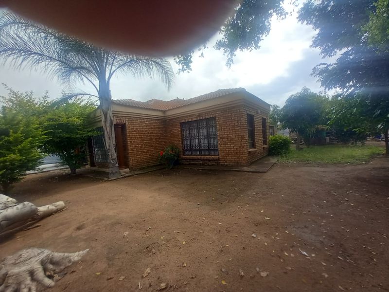 A view of the rear face brick exterior of the house, featuring a tiled roof and security bars on the windows.