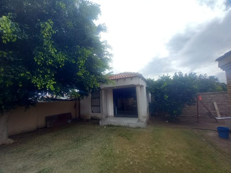 Rear view of the property featuring a covered patio area with concrete columns, sliding glass doors, and a private garden space.