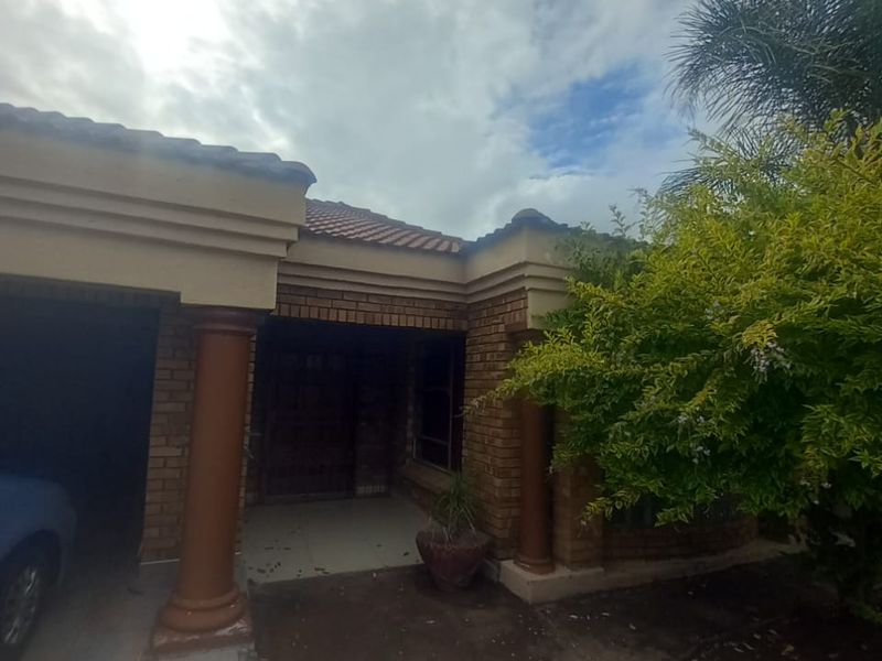 Front elevation of a brick house featuring a covered entrance, decorative columns, and a paved driveway area.