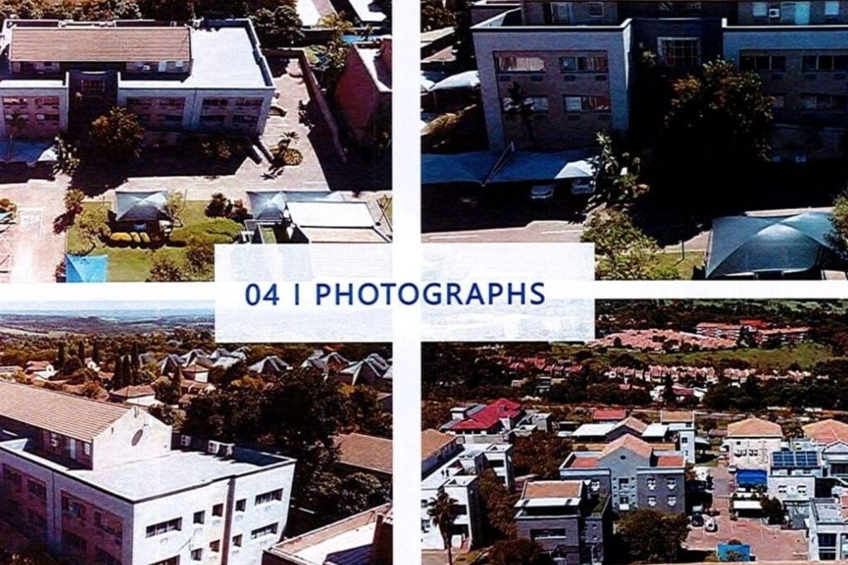 Aerial view of a commercial property complex featuring multiple buildings, tiled roofing, and paved parking areas within a suburban setting.