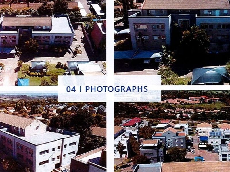 Aerial view of a commercial property complex featuring multiple buildings, tiled roofing, and paved parking areas within a suburban setting.