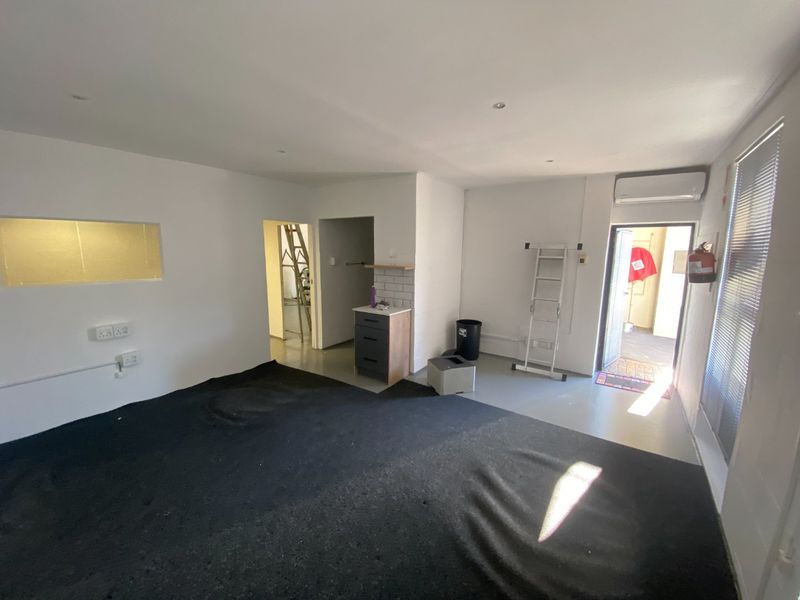 Open-plan office space featuring a small kitchenette vanity, split-system air conditioning, and recessed lighting, currently in a vacant, partially finished state.
