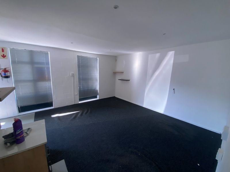 A clean, empty office space featuring exposed blockwork walls, recessed downlighting, and venetian blinds, providing a versatile industrial workspace.