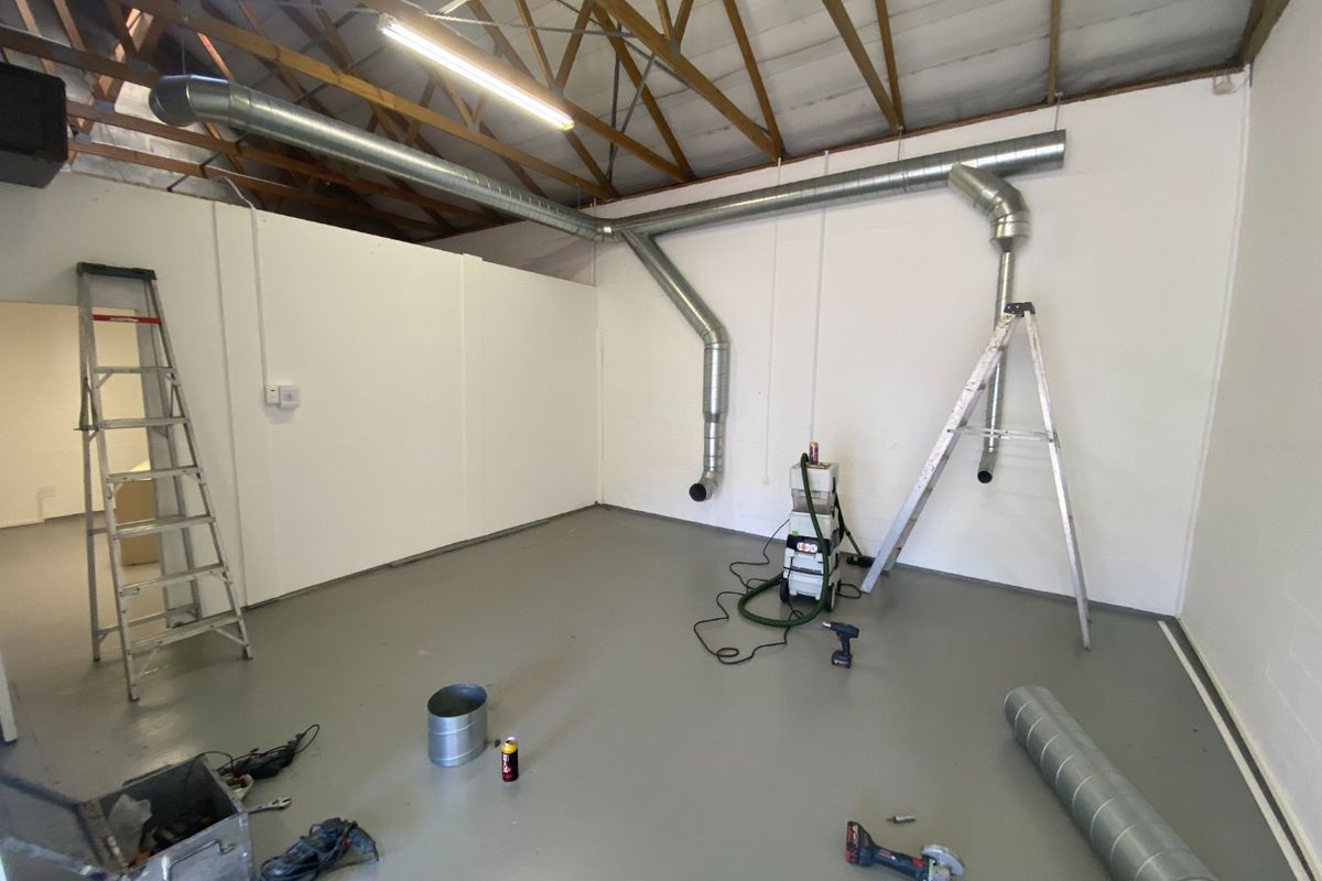 Industrial utility space featuring exposed timber roof trusses, galvanized steel ducting, and a durable epoxy-coated concrete floor.
