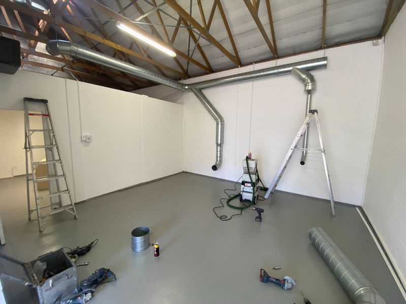 Industrial utility space featuring exposed timber roof trusses, galvanized steel ducting, and a durable epoxy-coated concrete floor.