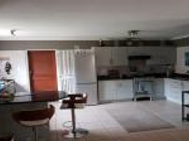 Open plan kitchen and living area featuring tiled flooring, built-in cabinetry, and a granite breakfast bar.