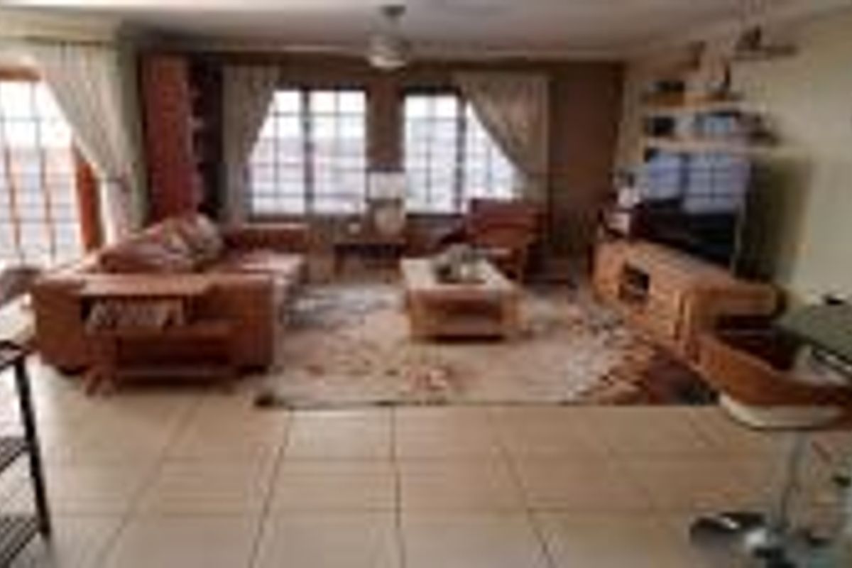 A spacious living room featuring tiled flooring, a ceiling fan, and access to an outdoor area through classic french doors.