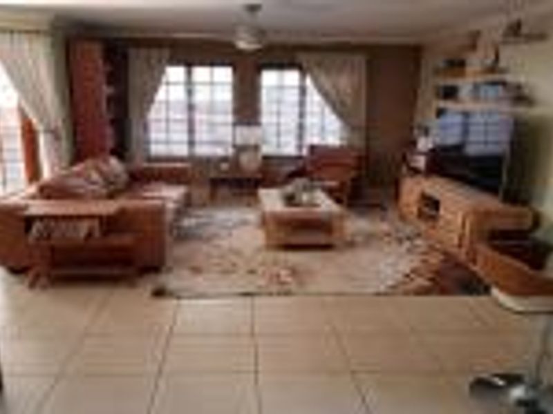 A spacious living room featuring tiled flooring, a ceiling fan, and access to an outdoor area through classic french doors.