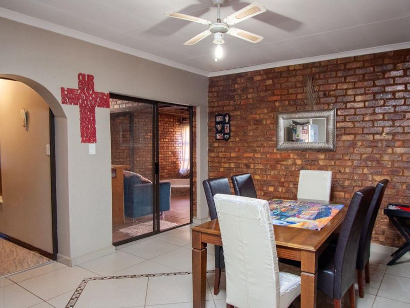 Dining area featuring exposed brick walls, tiled flooring, a ceiling fan, and sliding glass door access to an adjacent room.