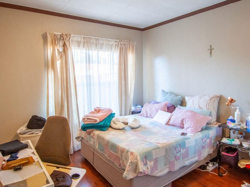 A standard bedroom featuring timber flooring and natural light through a window with curtain tracks.