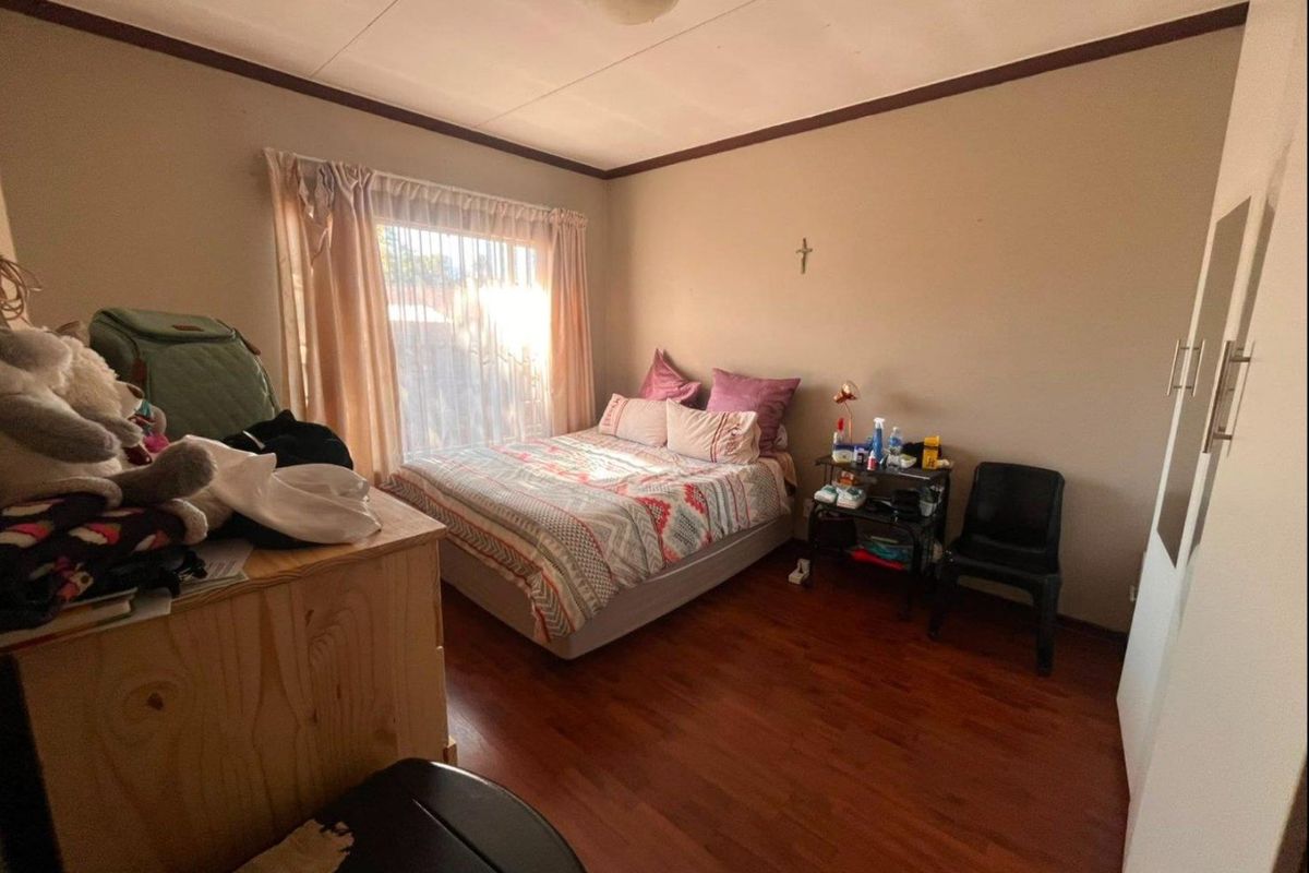 A standard bedroom featuring laminate flooring, a built-in wardrobe, and a window with curtains, providing a functional living space.
