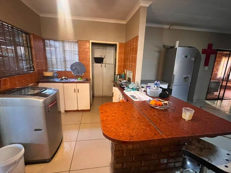 A functional kitchen featuring a breakfast bar with a brick base, tiled splashbacks, built-in cabinetry, and a separate pantry area.