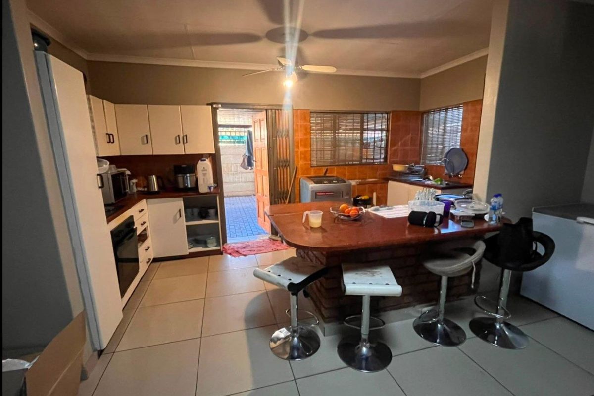 A functional kitchen featuring built-in cabinetry, a brick breakfast bar, tiled backsplash, and direct access to an outdoor area.
