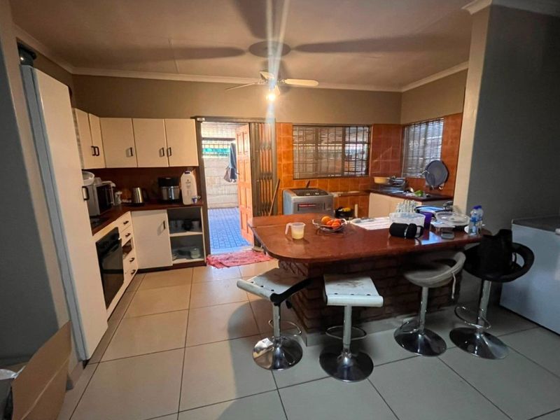 A functional kitchen featuring built-in cabinetry, a brick breakfast bar, tiled backsplash, and direct access to an outdoor area.