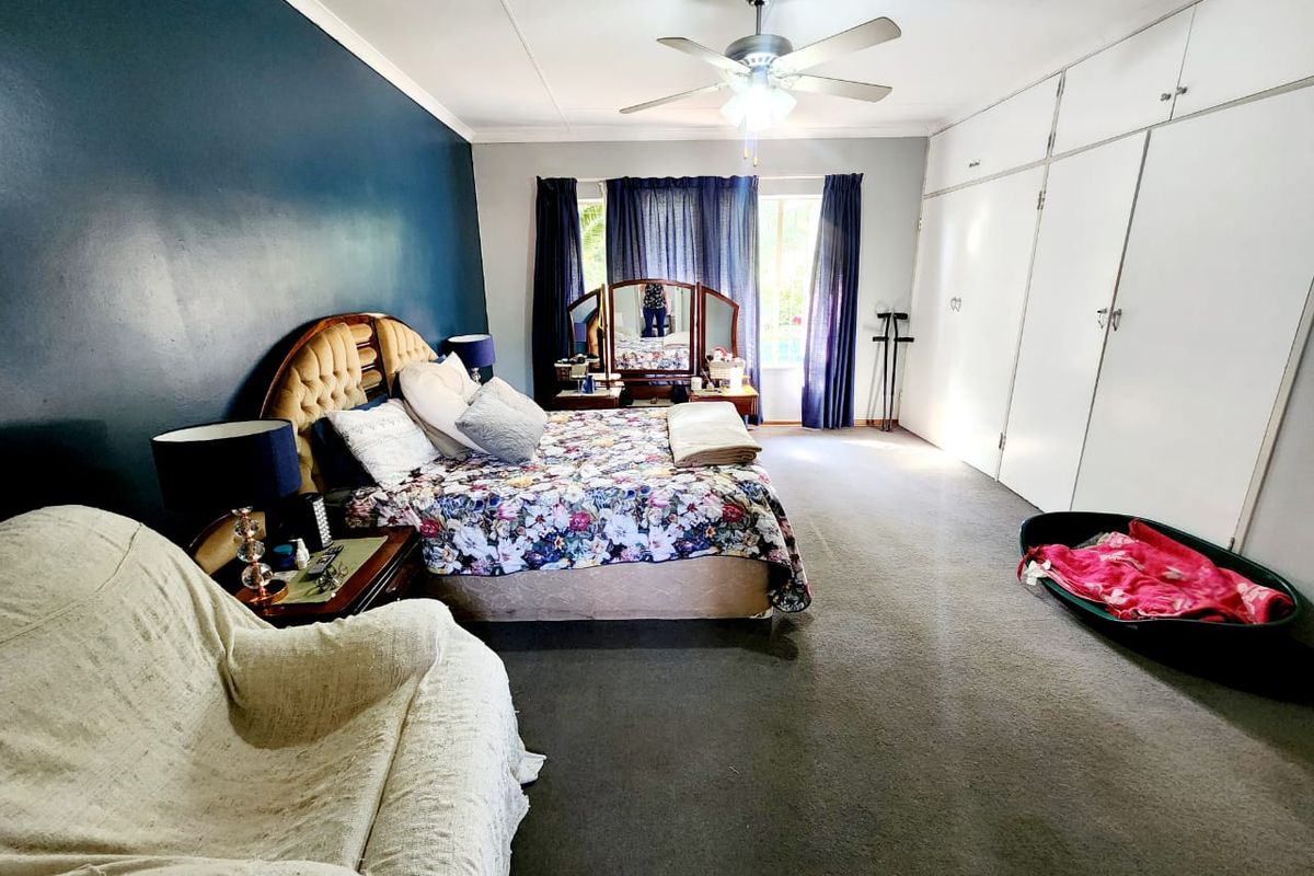 Spacious bedroom featuring built-in cupboards, a ceiling fan, and carpeted flooring, offering a comfortable layout with ample storage space.